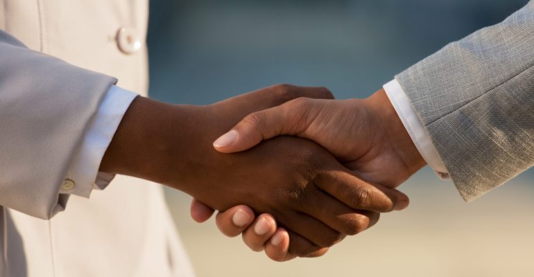 Dark skinned businesswoman shaking hands with male colleague